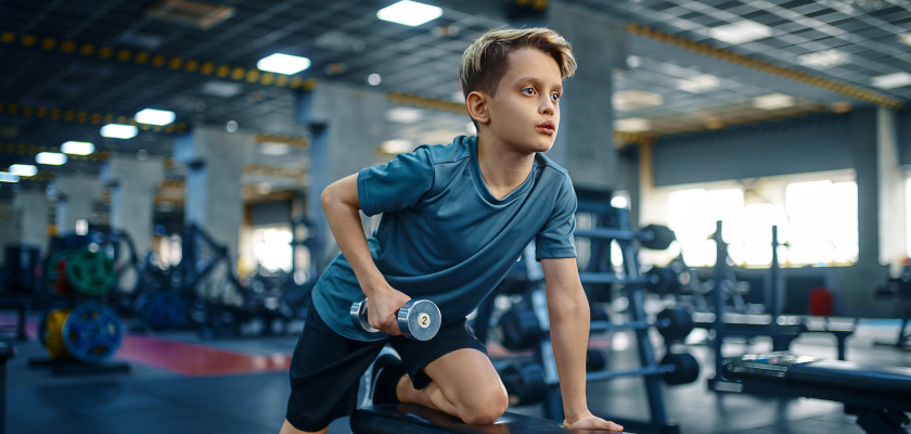Boy with dumbbell in a gym